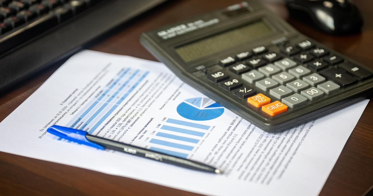 A desk with a calculator, a financial report and a pen