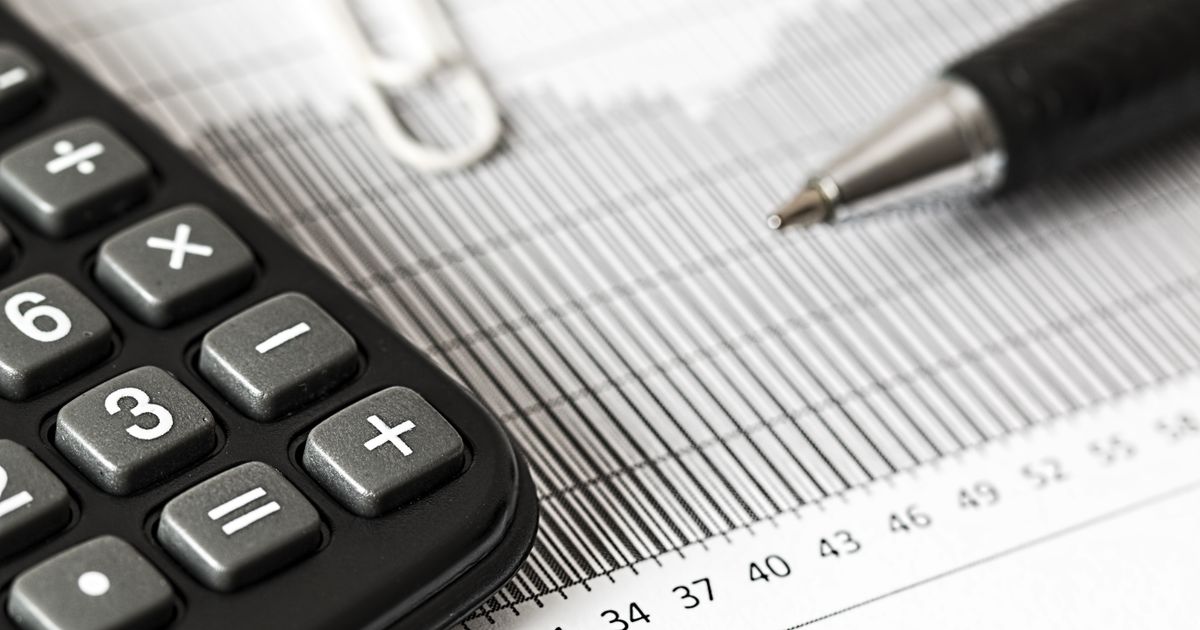 Close-up of a calculator and a pen resting on a printed table of figures