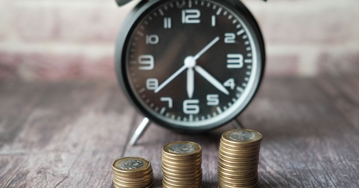 Stacks of coins beside an alarm clock