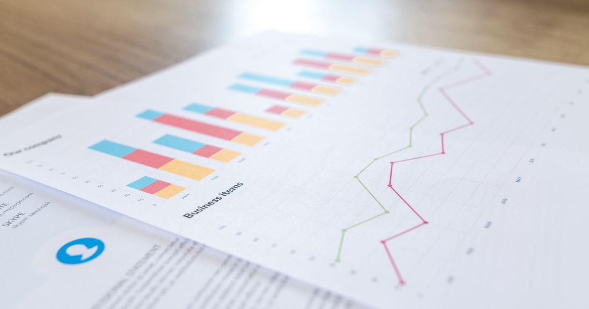 Printed bar and line charts lying on a wooden desk